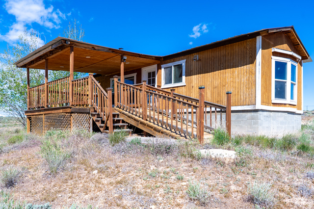 700 East Peter Springs Road Monticello, UT 84535 - Photo 34 of 57 Wood-sided structure featuring a covered wooden deck with railings, an exterior staircase, and a bay window