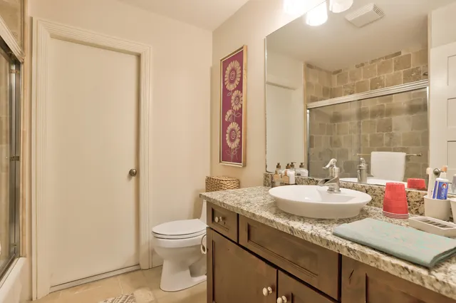 a bathroom with a granite countertop sink a toilet and a shower