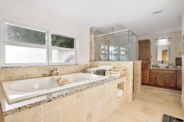 a spacious bathroom with a granite countertop sink mirror and bathtub