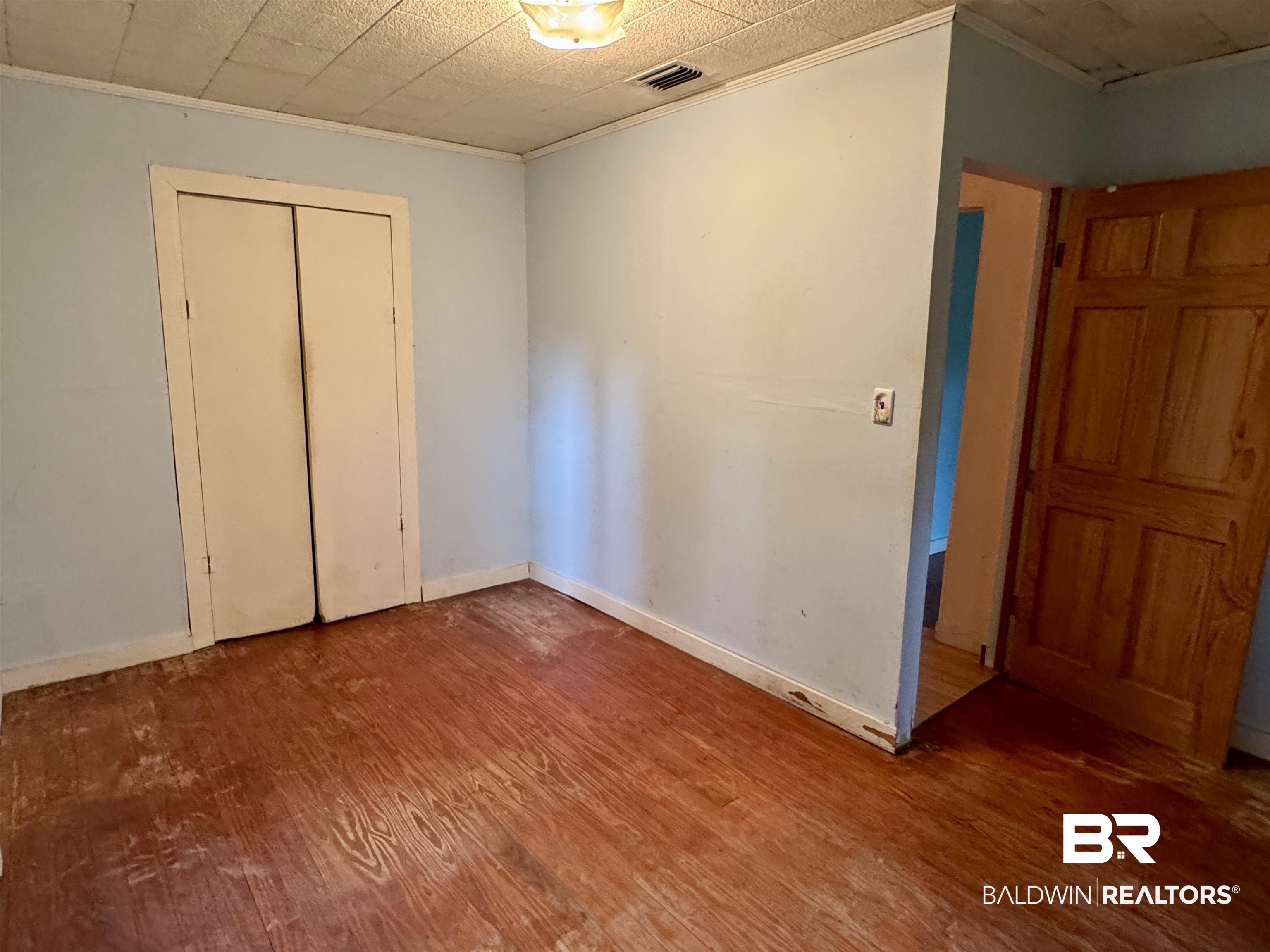 42186 Nicholsville Road Bay Minette, AL 36507 - Photo 9 of 10 Unfurnished bedroom with wood finished floors, crown molding, baseboards, and a closet