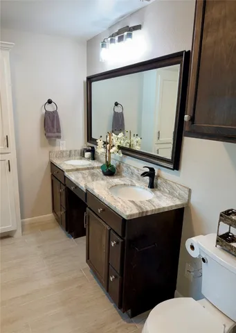 a bathroom with a granite countertop toilet sink and mirror