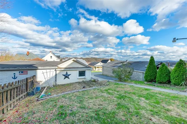 a view of a house with a yard and wooden fence