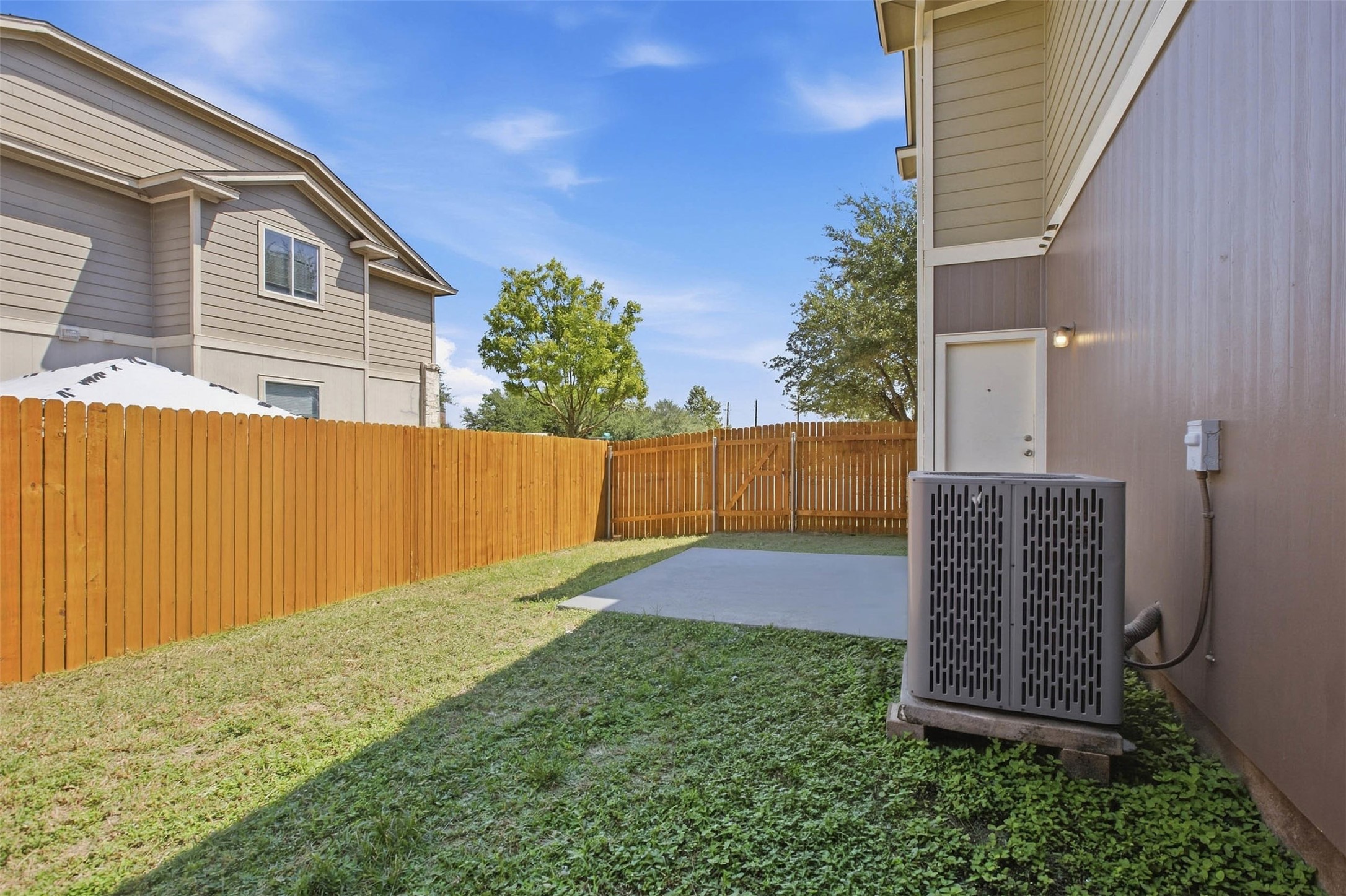 13808 Harris Ridge Boulevard, Unit B Pflugerville, TX 78660 - Photo 28 of 33 A wooden privacy fence surrounds the grassy backyard with a concrete patio slab.