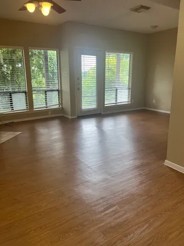 an empty room with wooden floor and windows