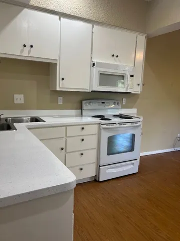 a kitchen with cabinets appliances and a wooden floor