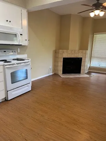 a view of kitchen with stainless steel appliances wooden floor and stove top oven