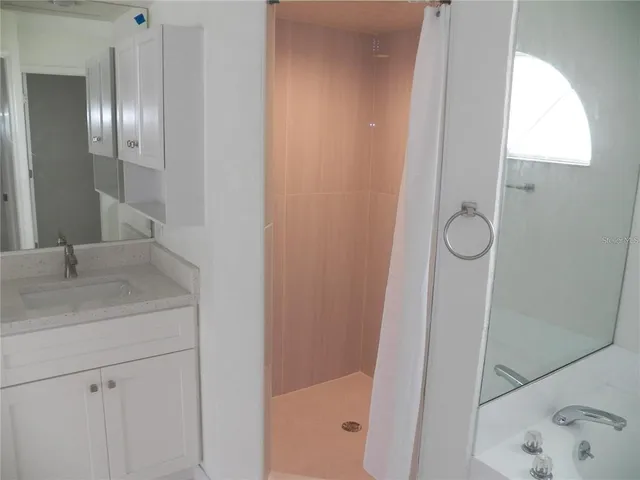 a bathroom with a granite countertop sink a mirror and shower