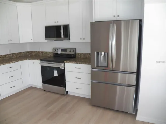 a kitchen with appliances a refrigerator and cabinets