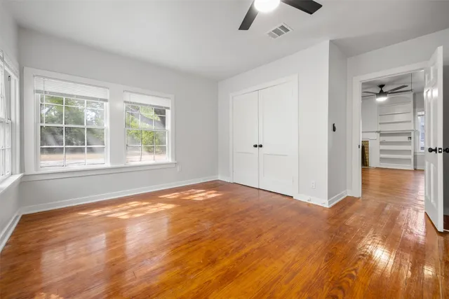 a view of an empty room with a window and hardwood floor