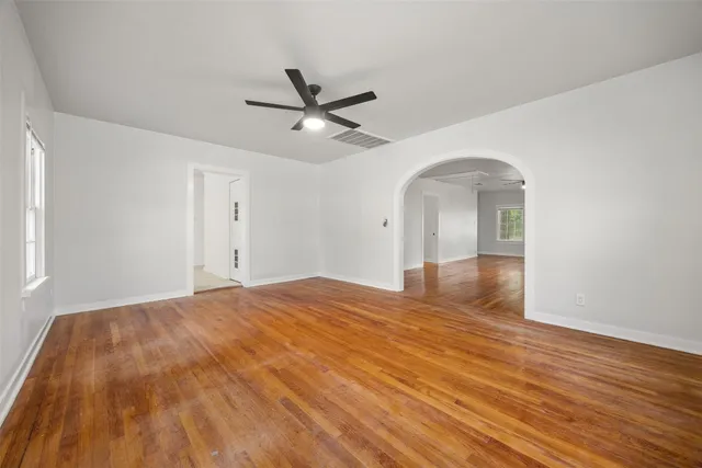 a view of empty room with wooden floor and fan