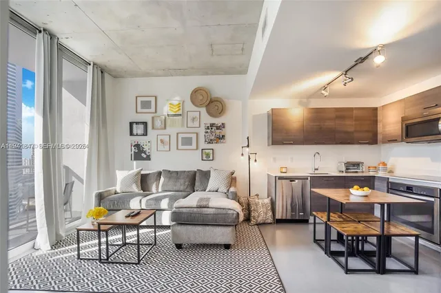 a living room with furniture a flat screen tv and kitchen view