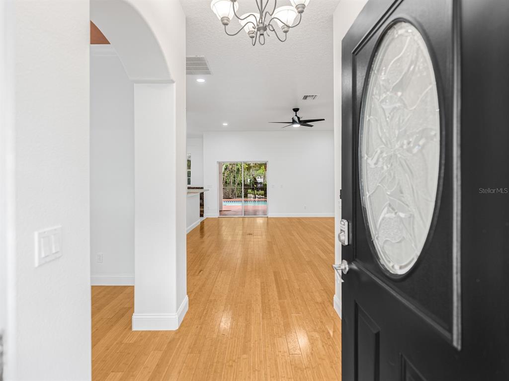 1670 Taylor Ridge Loop Kissimmee, FL 34744 - Photo 4 of 36 an entryway with wooden floor mirror and a chandelier