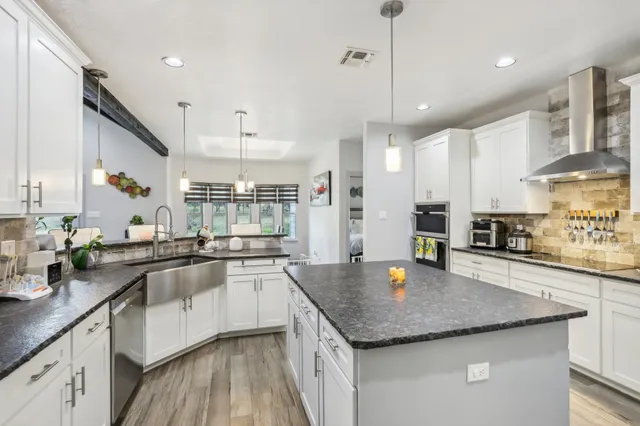 a kitchen with stainless steel appliances granite countertop stove top oven a sink and dishwasher with wooden floor
