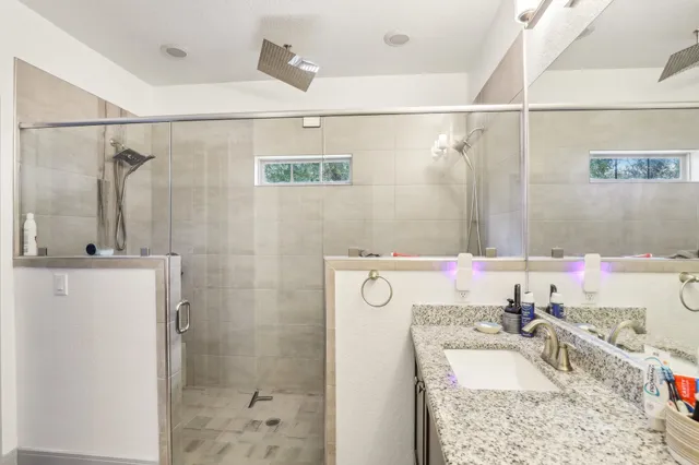 a bathroom with a granite countertop sink a mirror and shower
