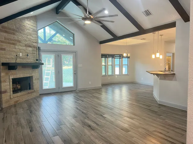an empty room with wooden floor a ceiling fan and windows
