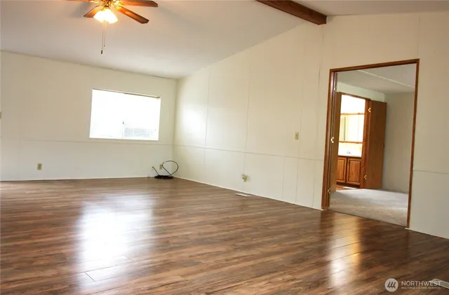 an empty room with wooden floor chandelier fan and windows