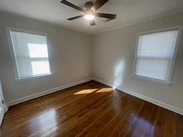 a view of empty room with wooden floor and fan