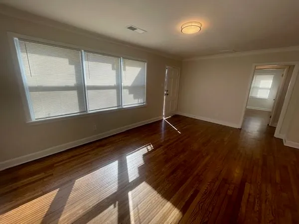 a view of an empty room with wooden floor and a window
