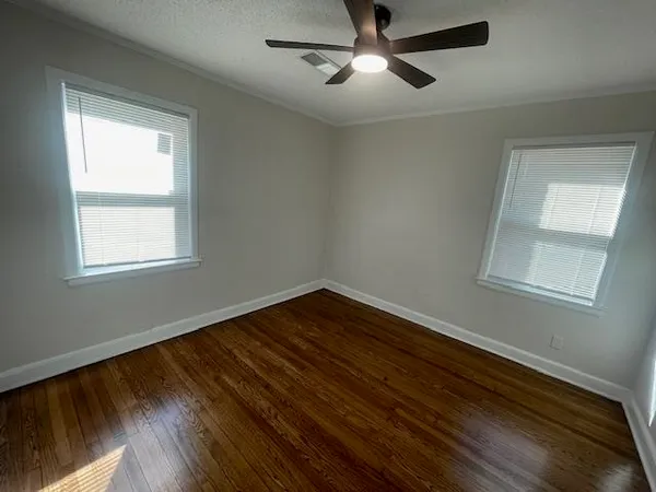 a view of an empty room with wooden floor and a window