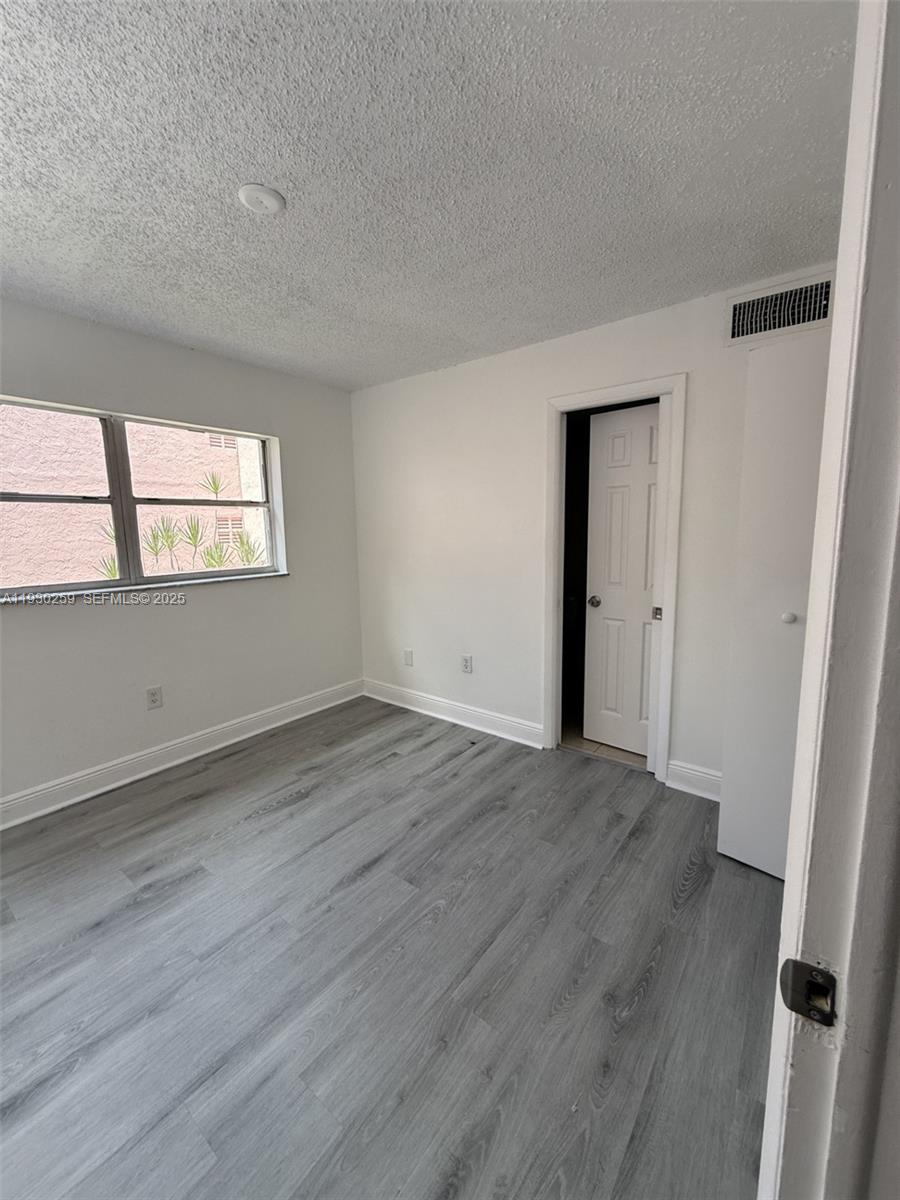 19729 Southwest 114th Avenue, Unit 251 Miami, FL 33157 - Photo 4 of 10 an empty room with wooden floor and windows
