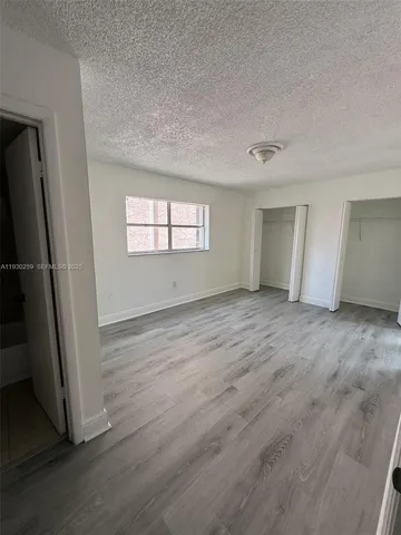 an empty room with wooden floor and window
