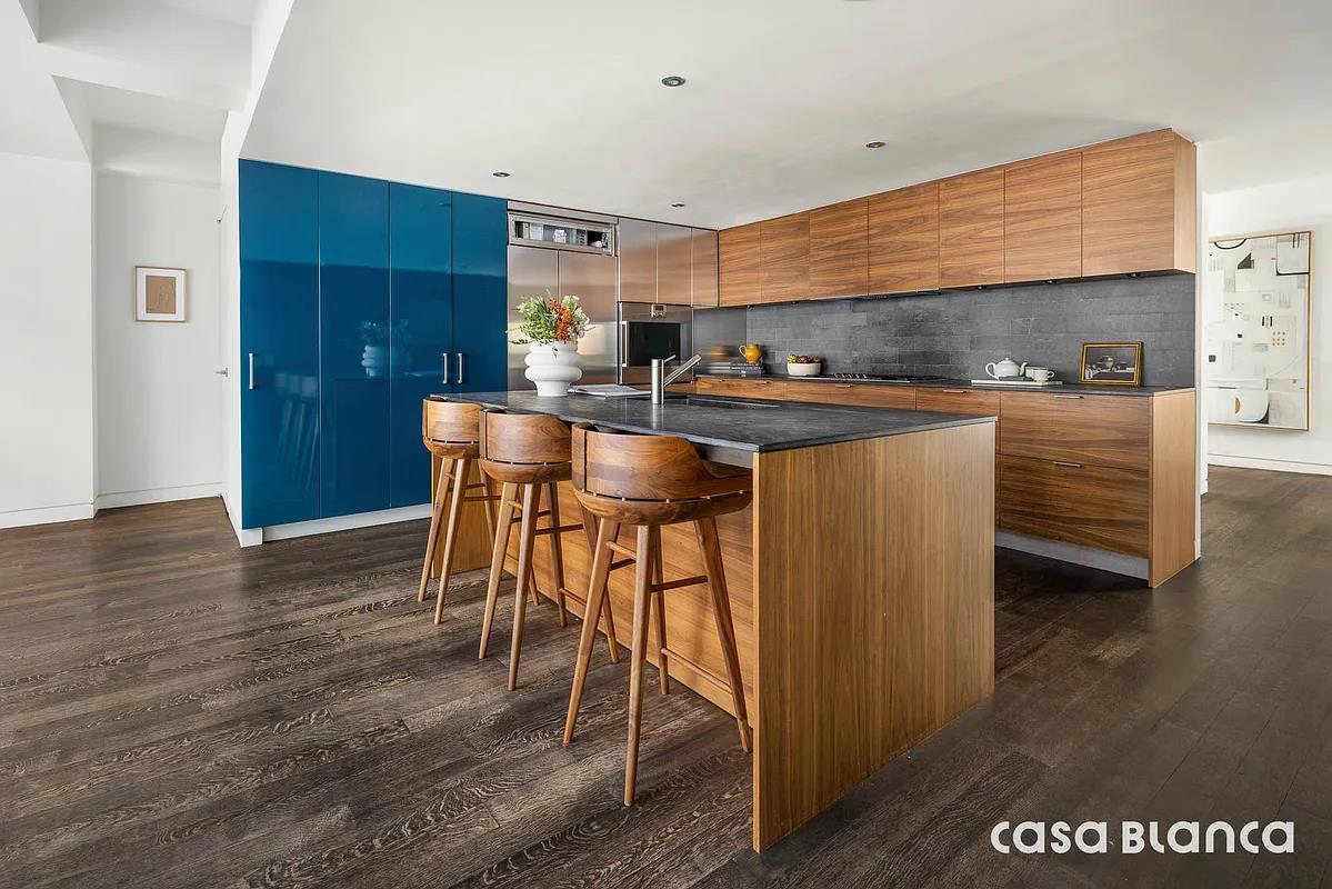 60 Collister Street, Unit PH5B Manhattan, NY 10013 - Photo 10 of 23 a kitchen with stainless steel appliances kitchen island granite countertop a table chairs sink and cabinets