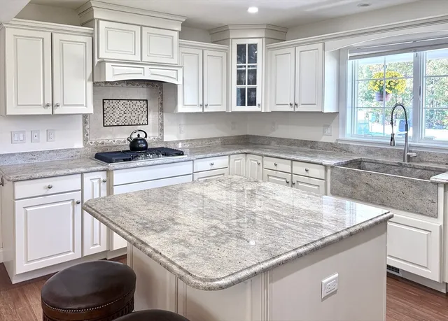 a kitchen with kitchen island granite countertop a sink a stove and cabinets