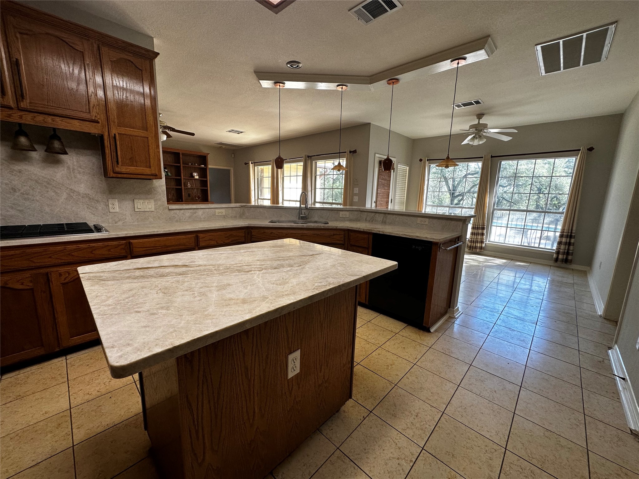13615 Copperleaf Trail Manchaca, TX 78652 - Photo 13 of 39 Kitchen with a ceiling fan, a peninsula, a center island, black appliances, and a textured ceiling