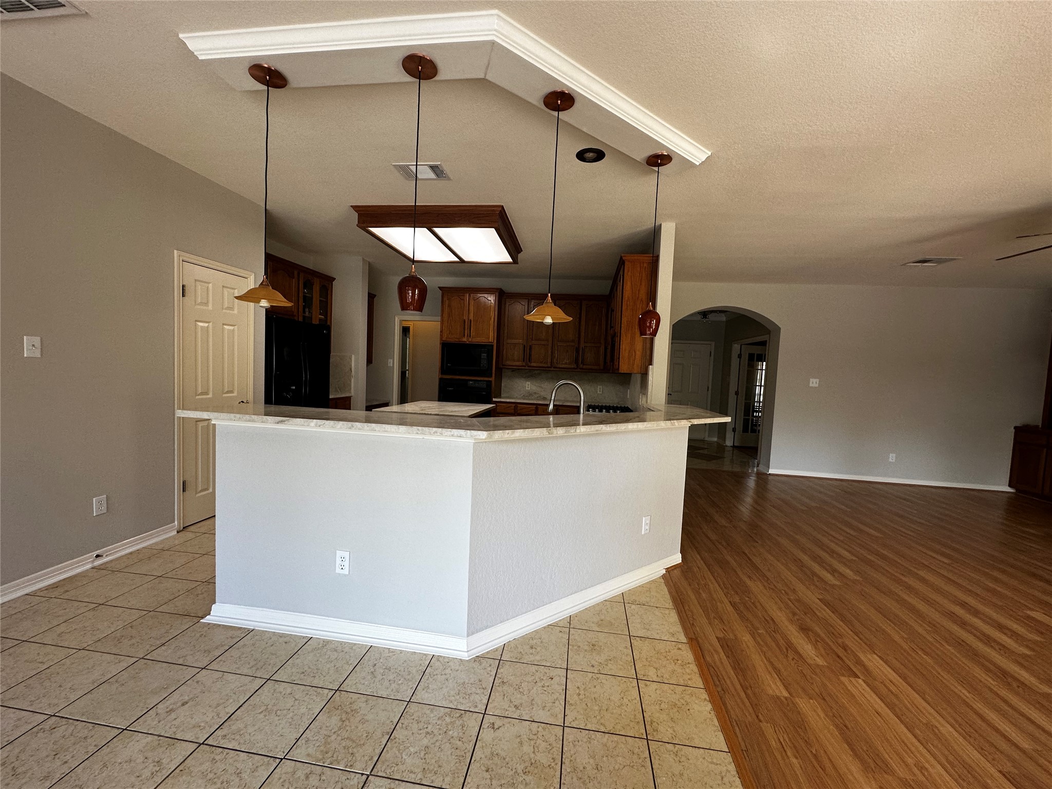 13615 Copperleaf Trail Manchaca, TX 78652 - Photo 17 of 39 Kitchen with arched walkways, light tile patterned flooring, black appliances, decorative light fixtures, and a textured ceiling