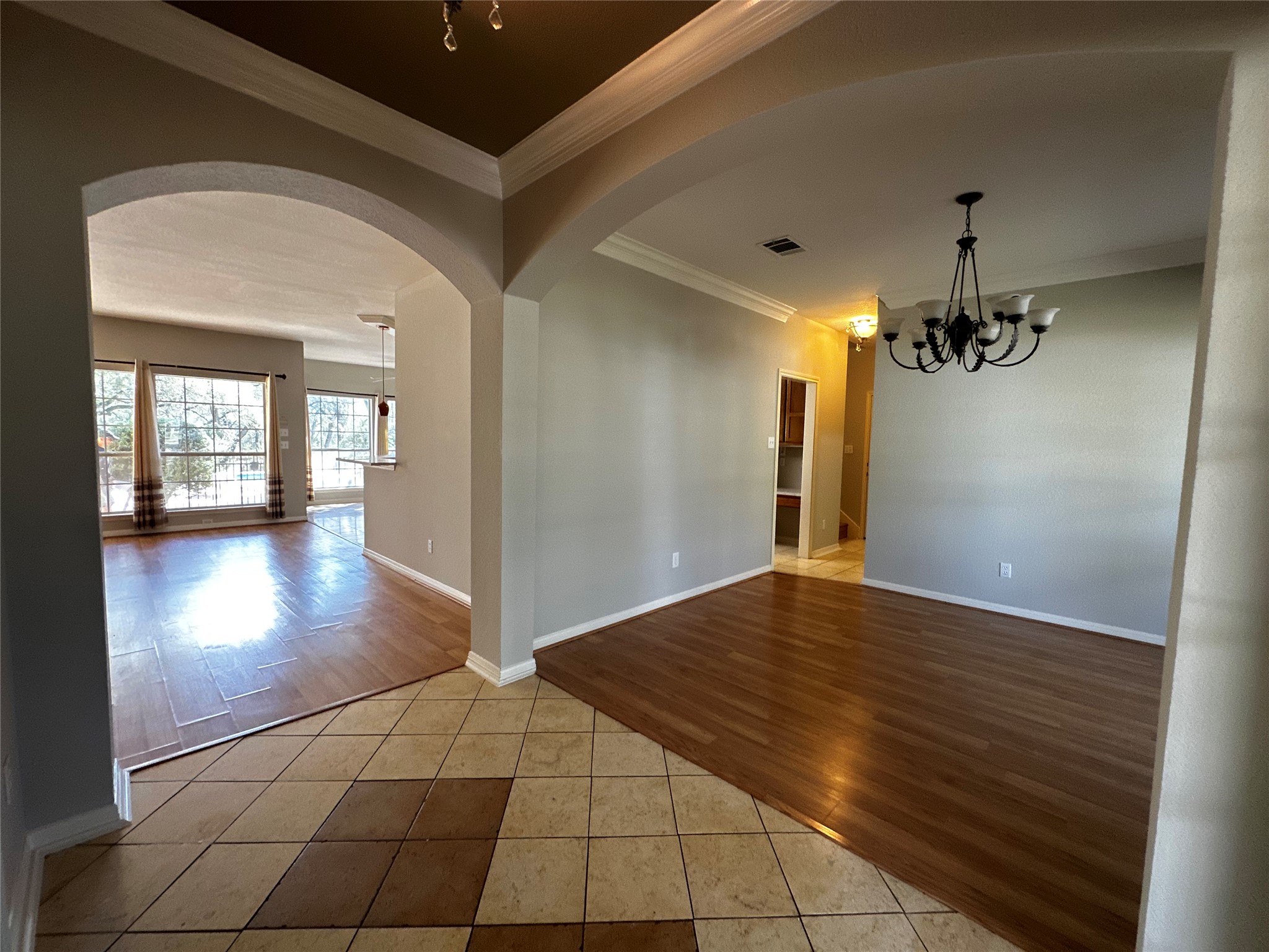 13615 Copperleaf Trail Manchaca, TX 78652 - Photo 4 of 39 Empty room with light tile patterned floors, arched walkways, hanging lights, and crown molding