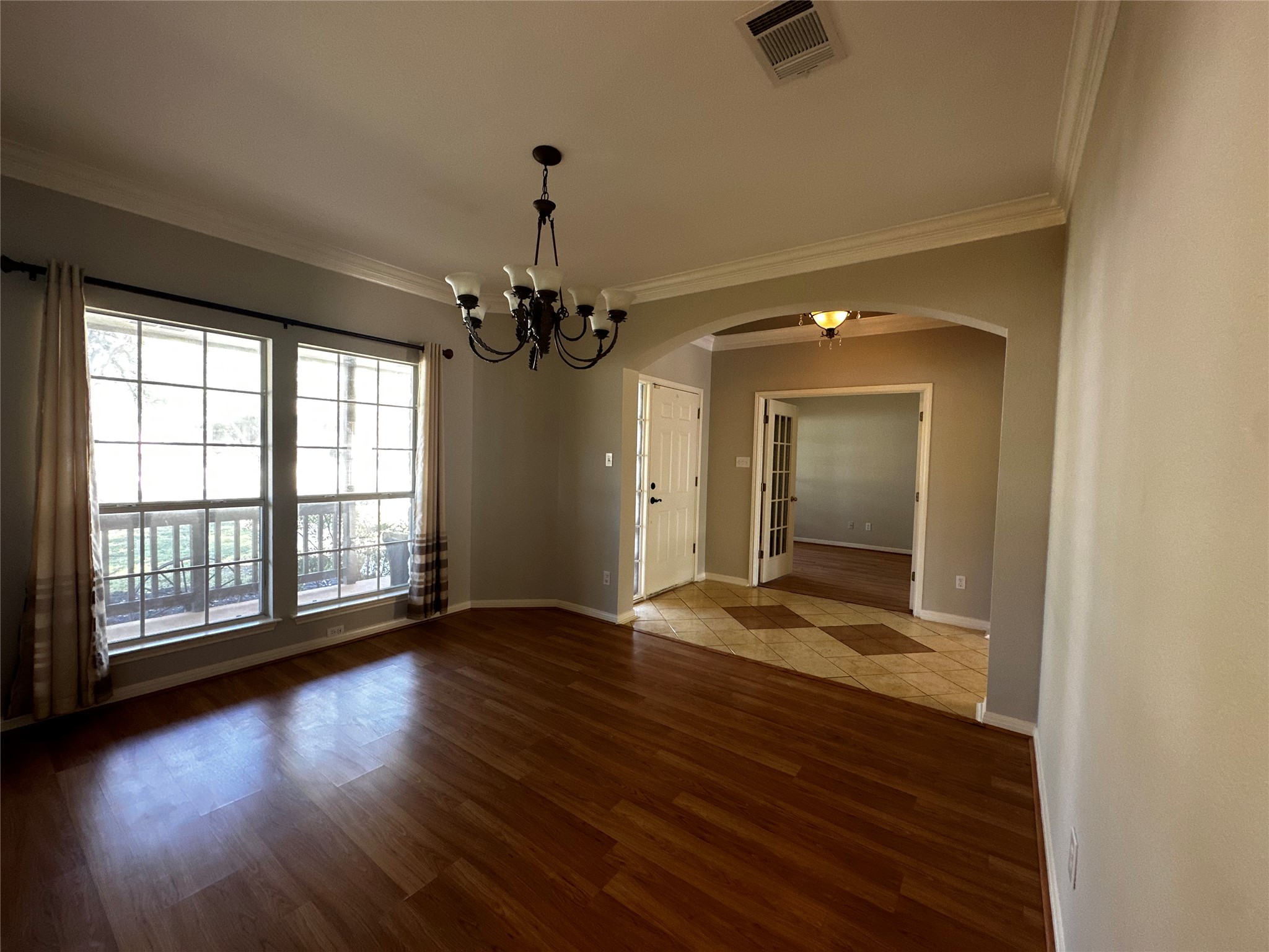 13615 Copperleaf Trail Manchaca, TX 78652 - Photo 6 of 39 Unfurnished dining area featuring a chandelier, crown molding, wood finished floors, and arched walkways