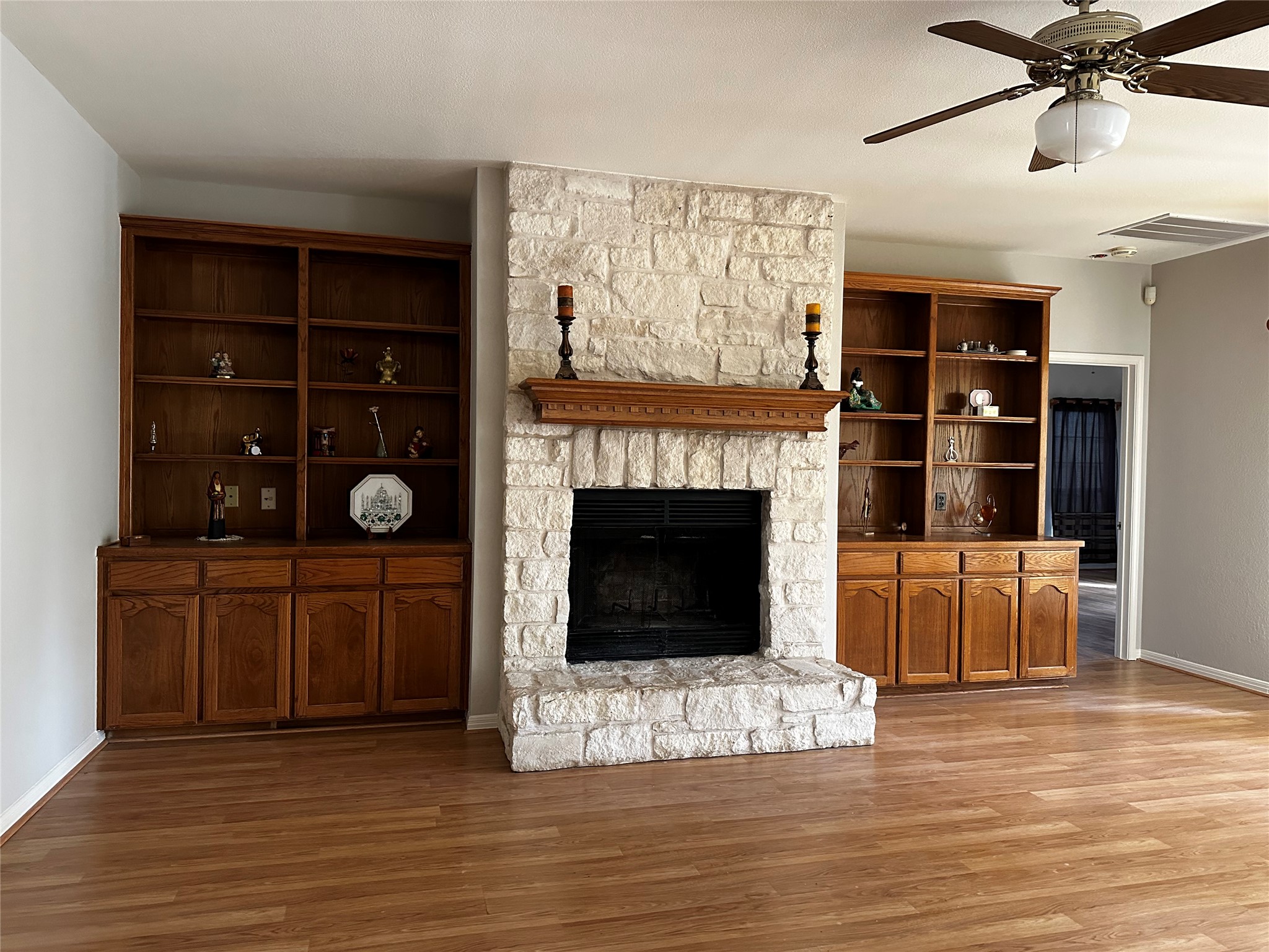13615 Copperleaf Trail Manchaca, TX 78652 - Photo 9 of 39 Unfurnished living room with a ceiling fan, a stone fireplace, and light wood-style floors