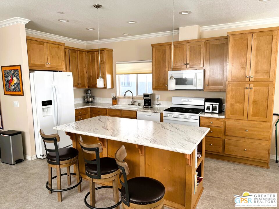 17640 Corkill Road, Unit 37 Desert Hot Springs, CA 92241 - Photo 11 of 35 a kitchen with stainless steel appliances a dining table chairs and refrigerator