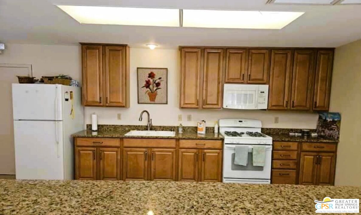 17640 Corkill Road, Unit 37 Desert Hot Springs, CA 92241 - Photo 31 of 35 a kitchen with stainless steel appliances granite countertop a stove a sink dishwasher and a refrigerator