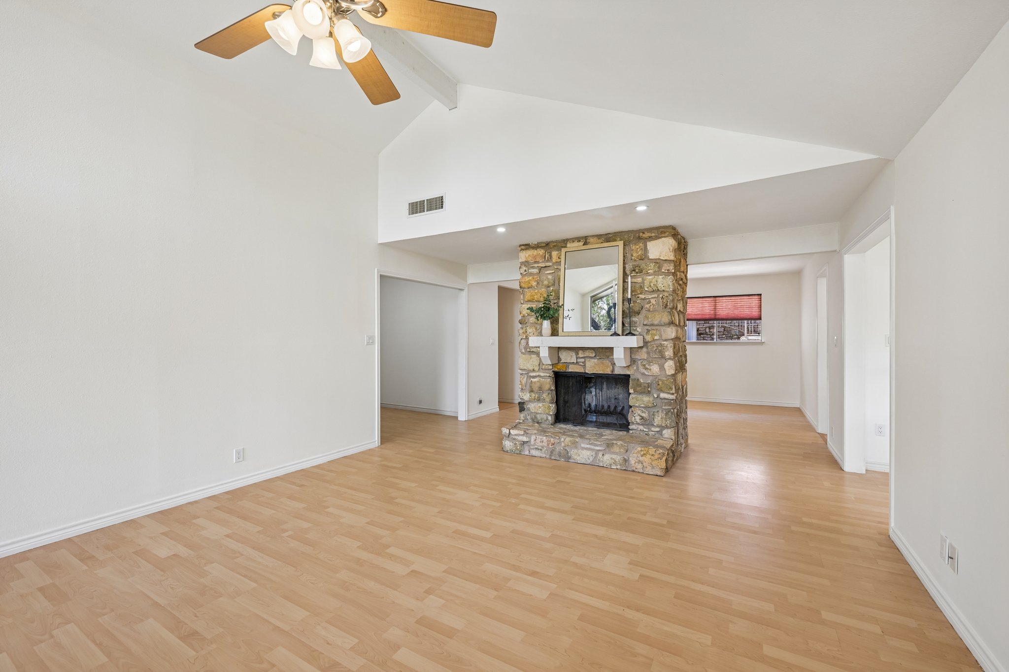13101 Travis View Loop Austin, TX 78732 - Photo 6 of 27 A striking stone fireplace anchors this living space with vaulted ceilings and light wood-look flooring.
