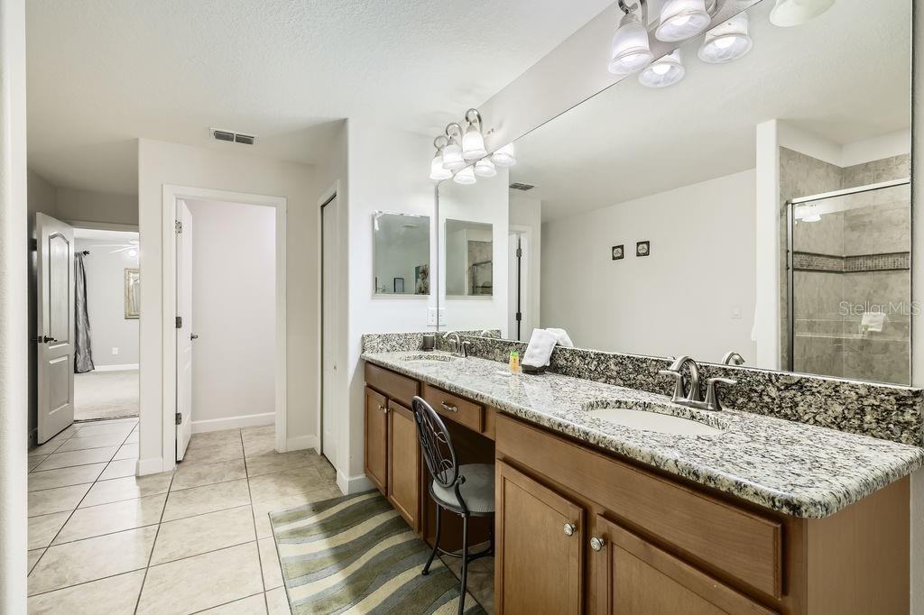 8989 Cuban Palm Road Kissimmee, FL 34747 - Photo 20 of 49 a bathroom with a granite countertop sink a large mirror and a shower