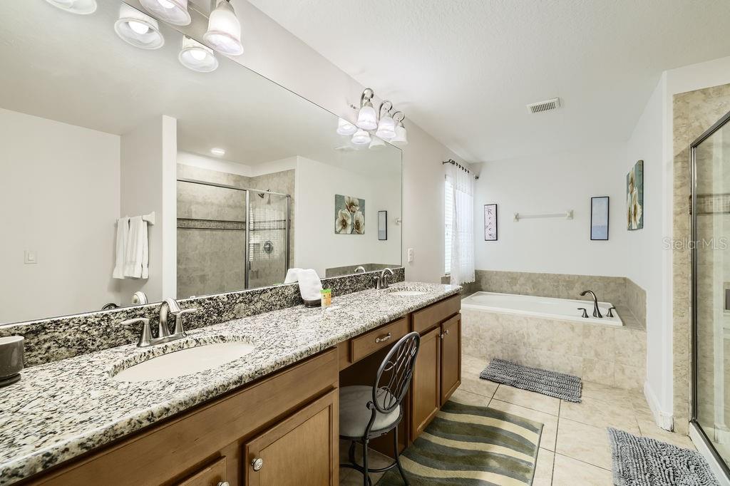 8989 Cuban Palm Road Kissimmee, FL 34747 - Photo 21 of 49 a bathroom with a granite countertop sink a large mirror and a bathtub