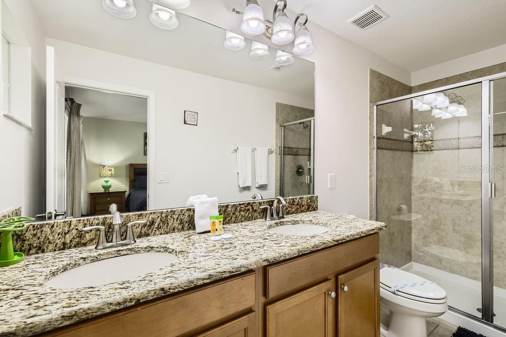 8989 Cuban Palm Road Kissimmee, FL 34747 - Photo 23 of 49 a bathroom with a granite countertop double vanity sink mirror and toilet