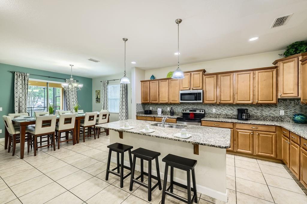 8989 Cuban Palm Road Kissimmee, FL 34747 - Photo 8 of 49 a kitchen with stainless steel appliances granite countertop a stove top oven a sink a dining table and chairs