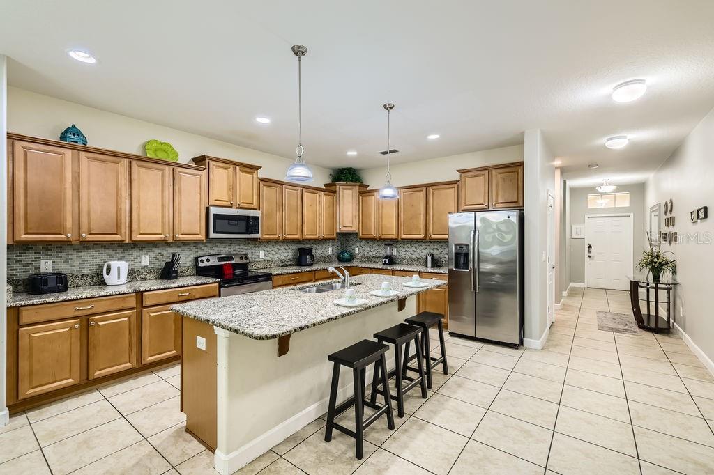 8989 Cuban Palm Road Kissimmee, FL 34747 - Photo 9 of 49 a kitchen with stainless steel appliances granite countertop a sink a stove a refrigerator and cabinets