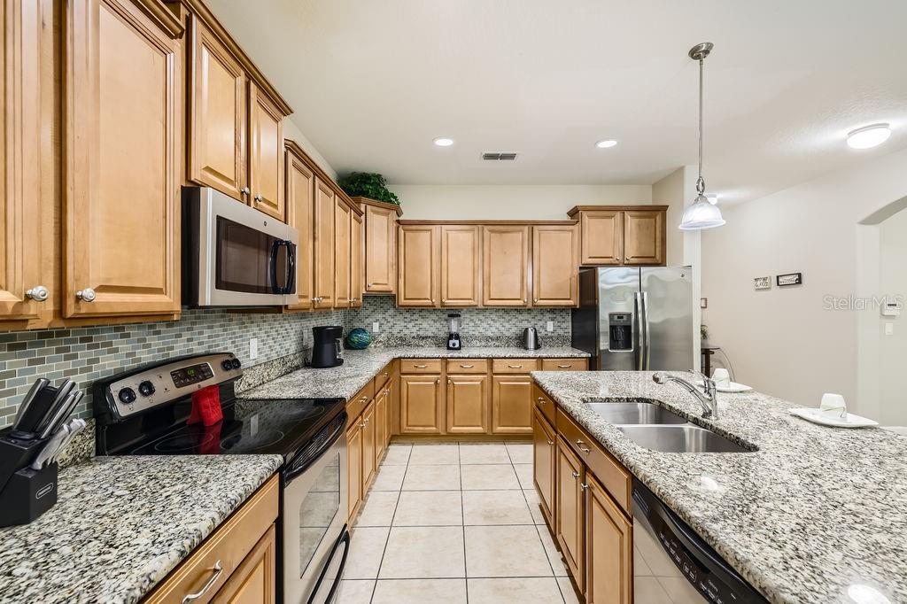 8989 Cuban Palm Road Kissimmee, FL 34747 - Photo 10 of 49 a kitchen with stainless steel appliances granite countertop a sink stove and refrigerator