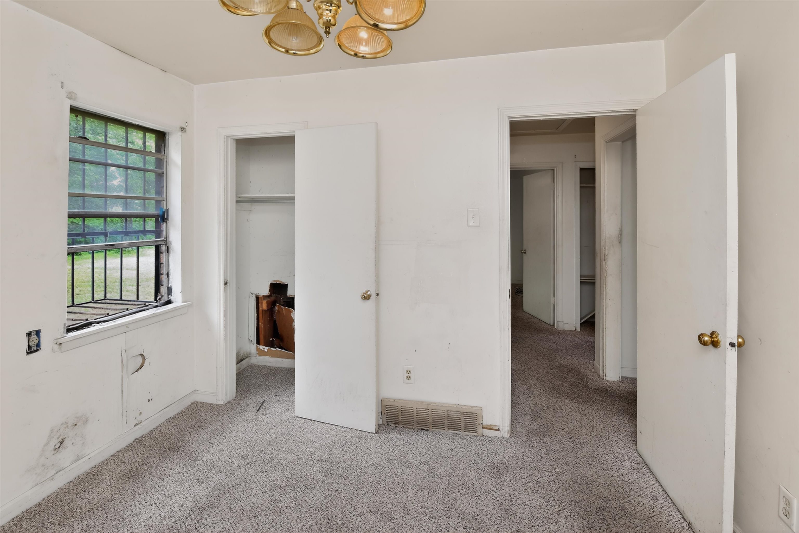 3451 Birdsong Ferry Road Memphis, TN 38118 - Photo 24 of 27 Carpeted interior room featuring a gold-toned ceiling light fixture, a window with exterior security bars, and two interior doors with gold-toned hardware