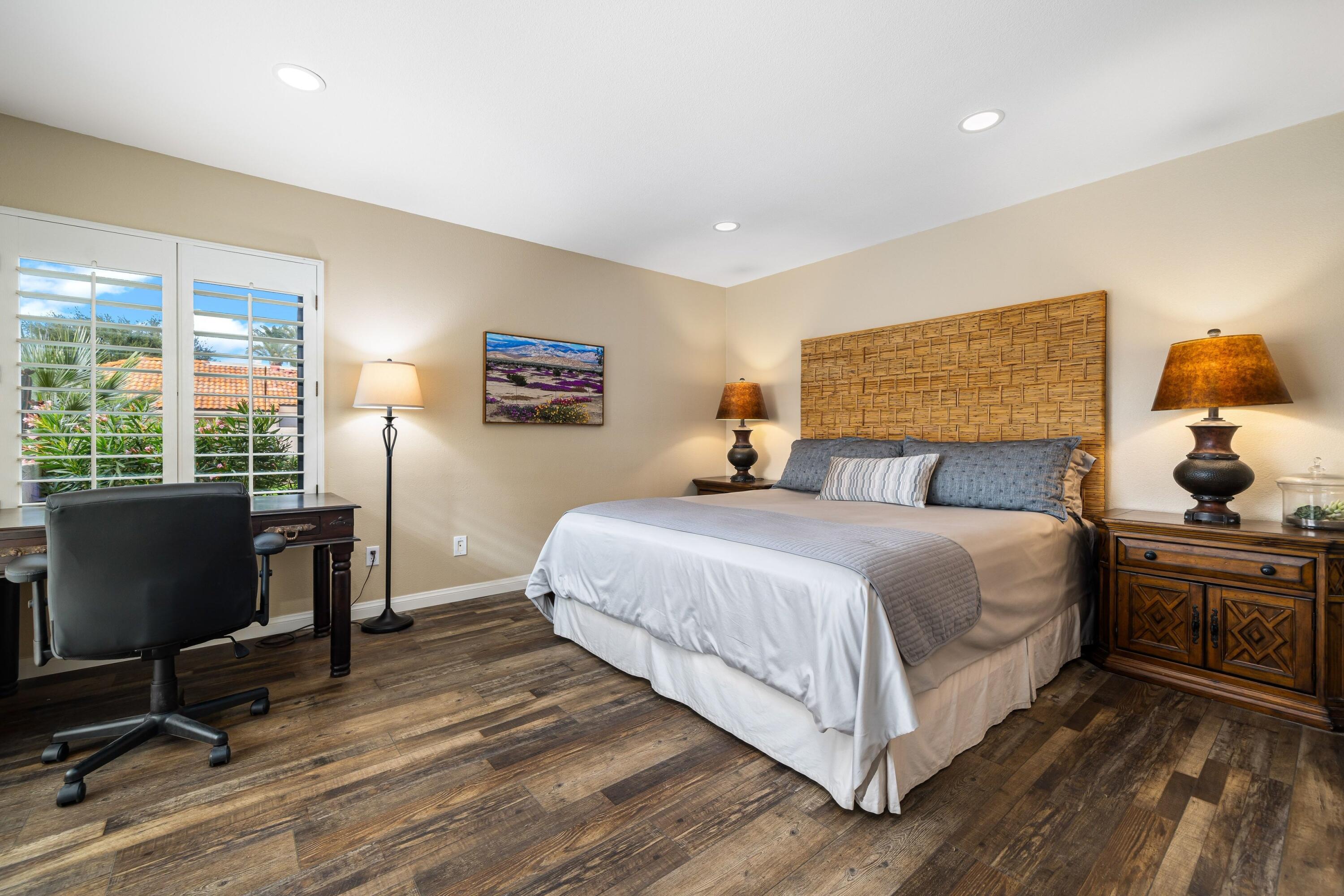 29 Verde Way Palm Desert, CA 92260 - Photo 14 of 43 a bedroom with a bed a desk and chair with wooden floor