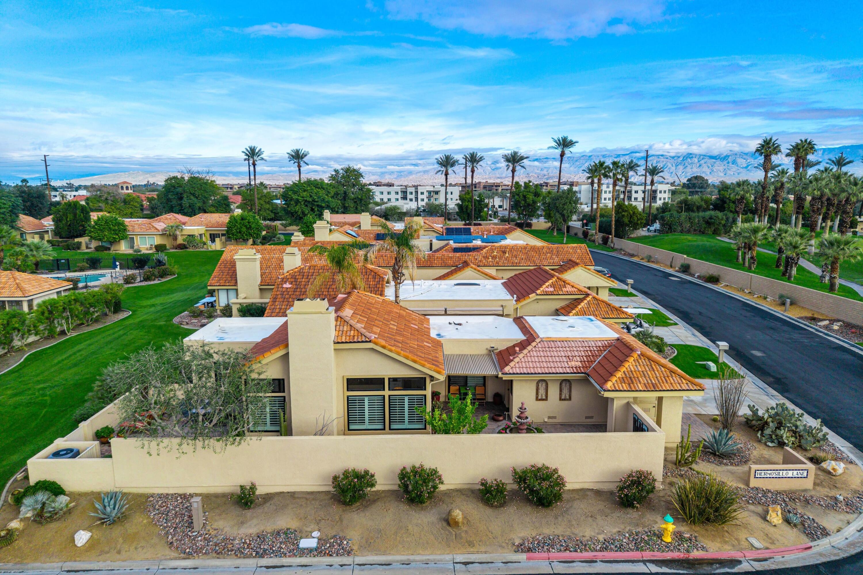 29 Verde Way Palm Desert, CA 92260 - Photo 34 of 43 a view of a white house next to a yard with plants and large trees