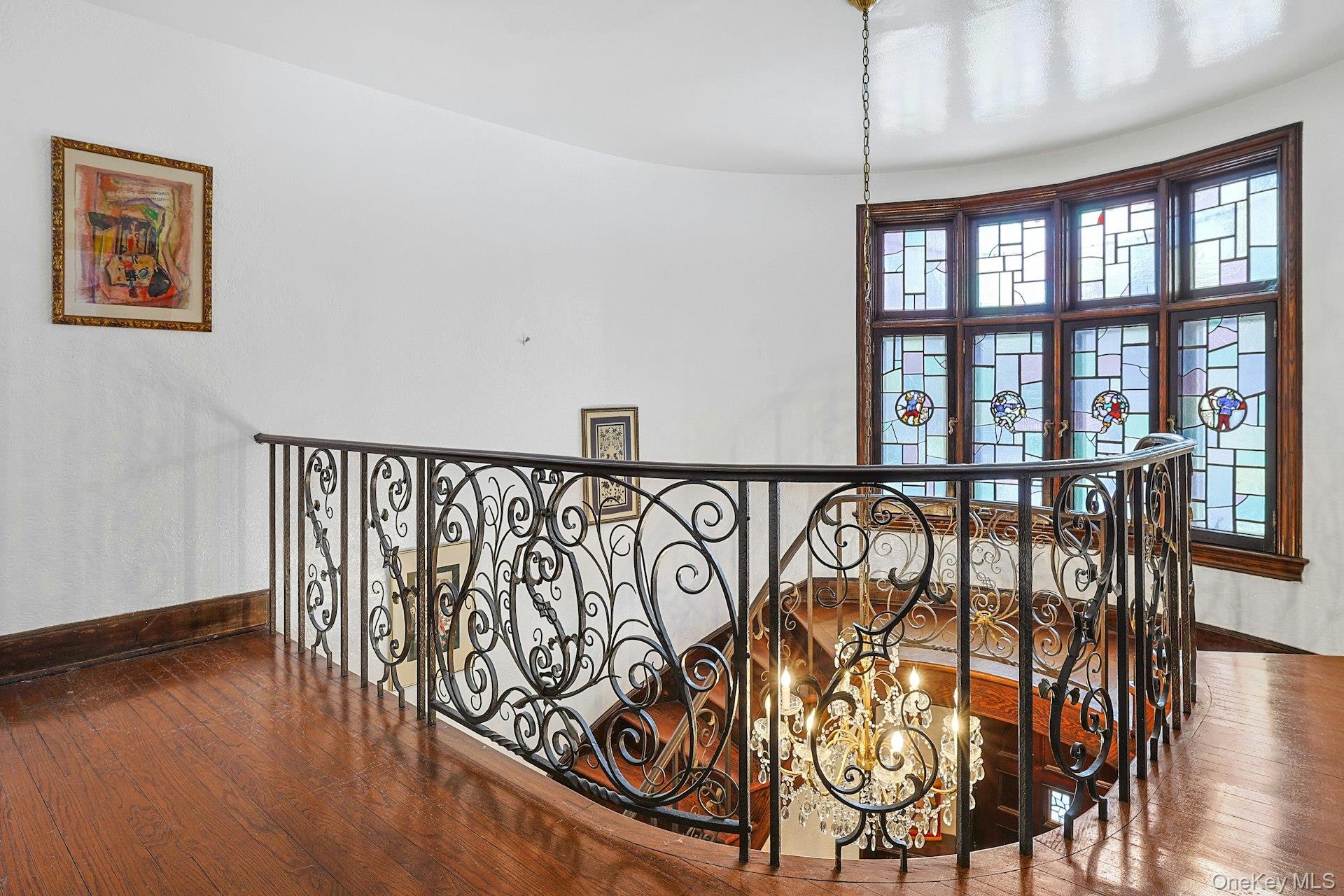 66 Mamaroneck Road Scarsdale, NY 10583 - Photo 20 of 47 The elegant second-level landing overlooks the sweeping staircase, where intricate wrought-iron detailing and stained-glass windows create a striking architectural focal point.