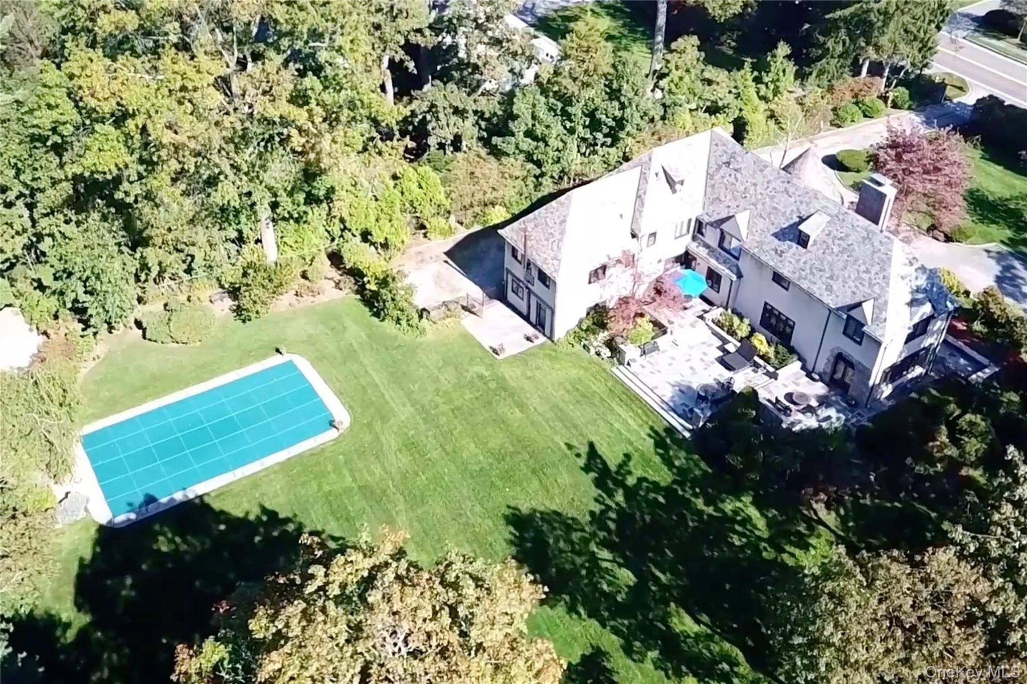 66 Mamaroneck Road Scarsdale, NY 10583 - Photo 3 of 47 From above, the full beauty of this level one-acre property unfolds—lush lawns, expansive patio spaces, and an inviting inground pool surrounded by mature landscaping.