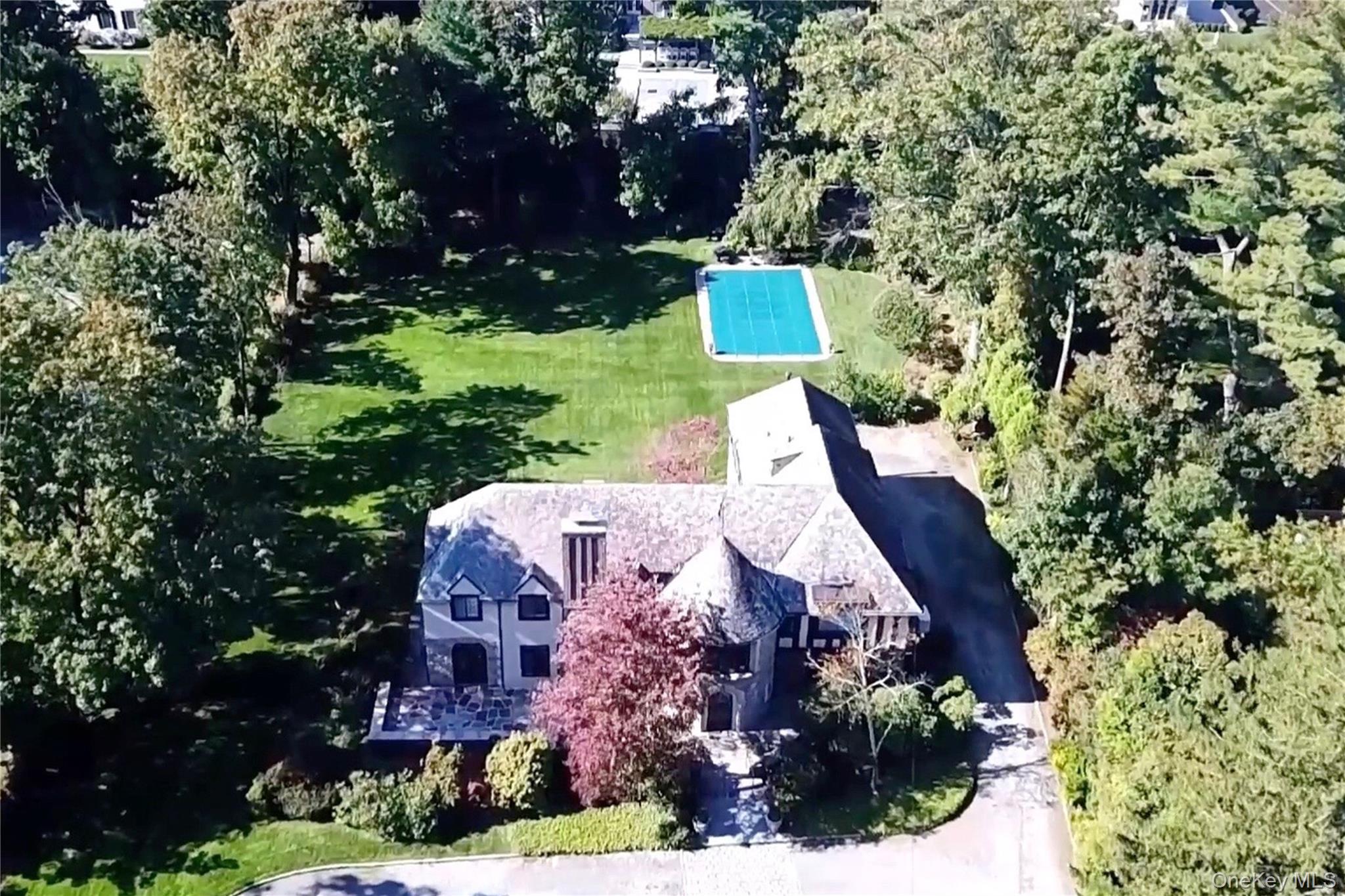66 Mamaroneck Road Scarsdale, NY 10583 - Photo 37 of 47 An aerial view captures the full scale and beauty of this estate property—showcasing the level one-acre setting, classic Tudor residence, and private pool surrounded by mature trees.