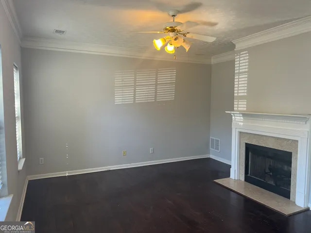 an empty room with wooden floor fireplace and fan