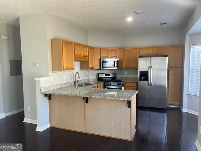 a kitchen with stainless steel appliances granite countertop a sink a stove a refrigerator cabinets and a center island