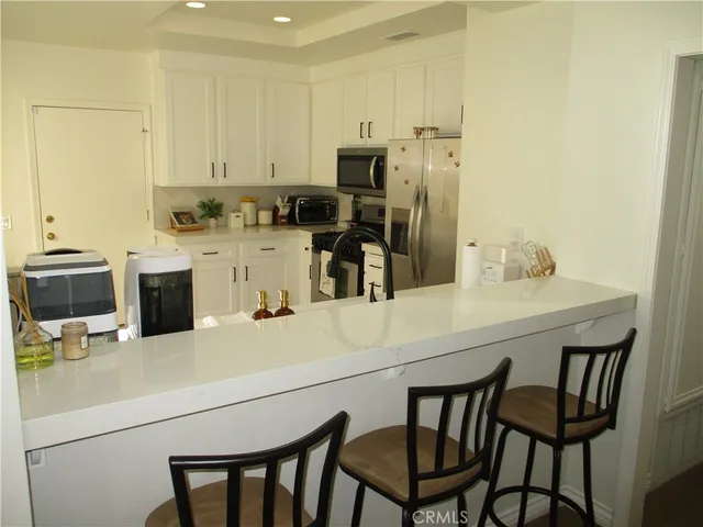 a kitchen with a table chairs microwave and cabinets